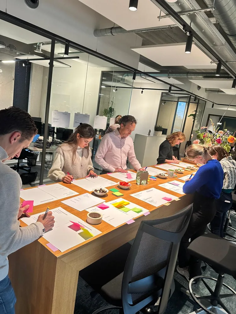 Deelnemers schrijven ideeën op grote werkvellen met gekleurde post-its